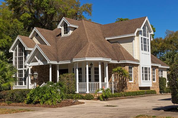 A large brown house with a white porch.