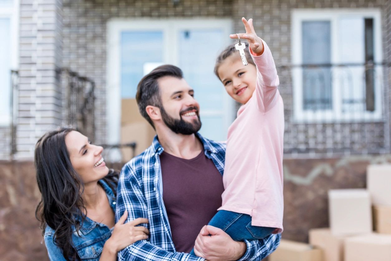 A young girl is holding up a key to her new home.