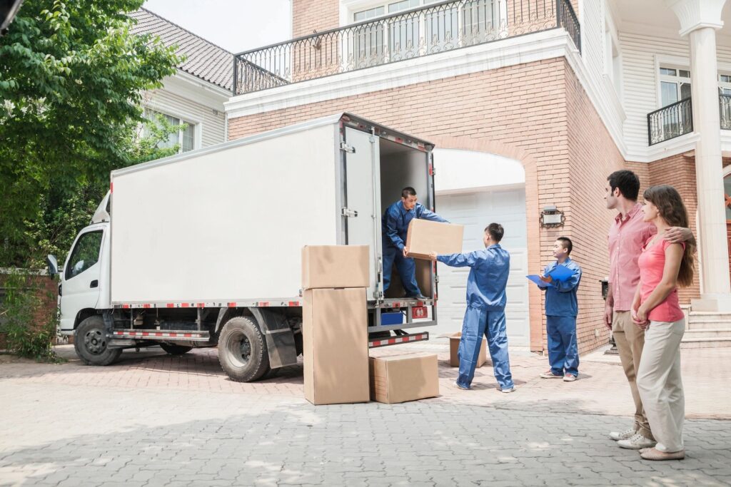 Two men unloading boxes from a moving truck.