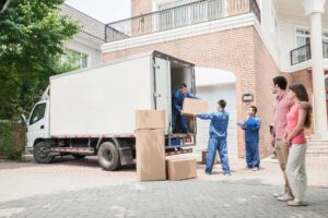 Two men unloading boxes from a moving truck.