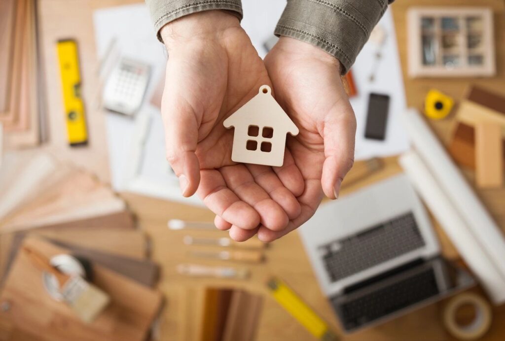 A person holding a small house in their hands.