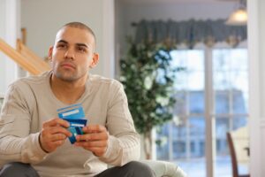 A man sitting on the couch holding a box of chewing gum.