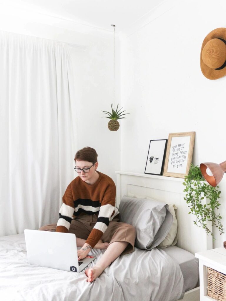 A person sitting on the bed with a laptop