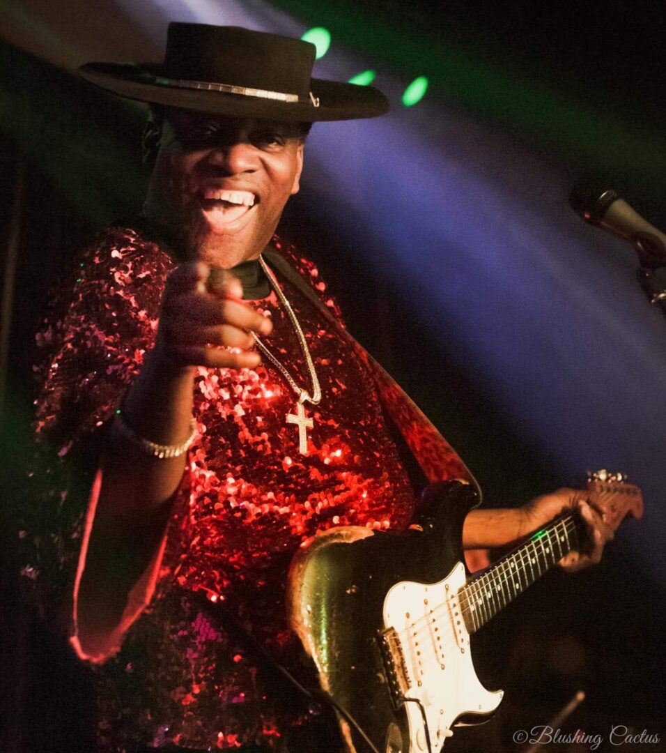 A man in red shirt holding a guitar.