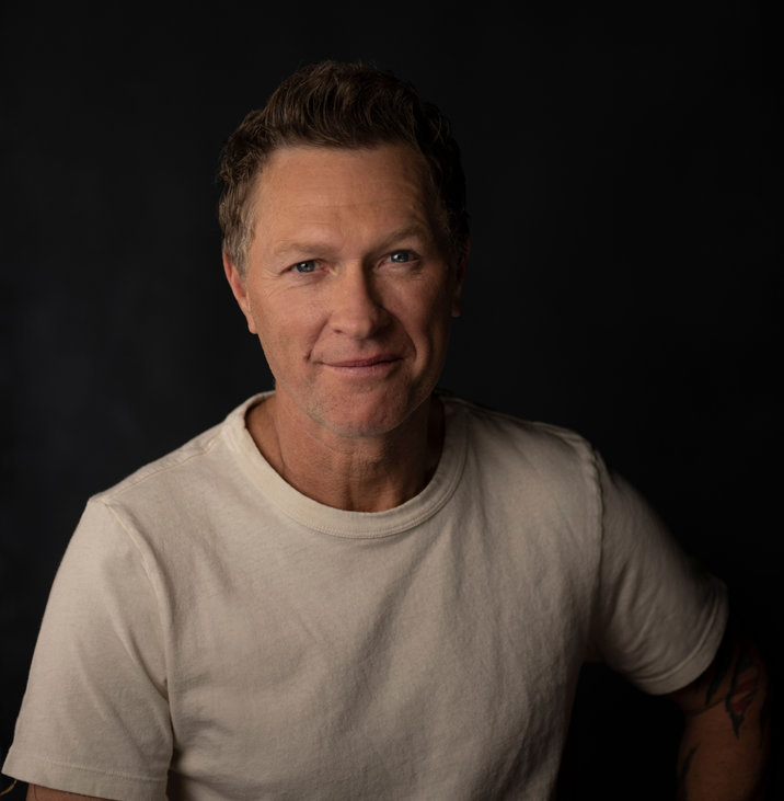 A man in white shirt standing next to black wall.