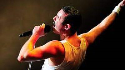 A man with his arms stretched out singing into a microphone.