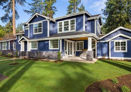 A blue house with white trim and green grass.