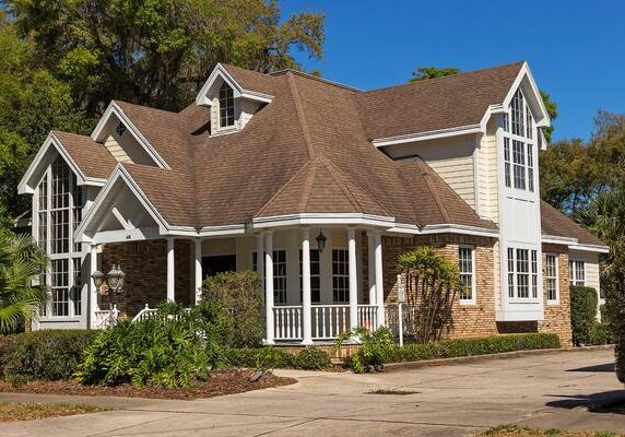 A large brown house with a white porch.